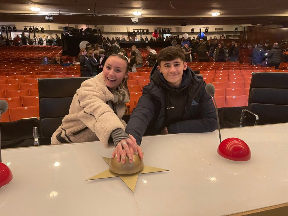 Two Coronation Street teen stars at the Britain's Got Talent judges' desk, hands on a golden star-shaped button.