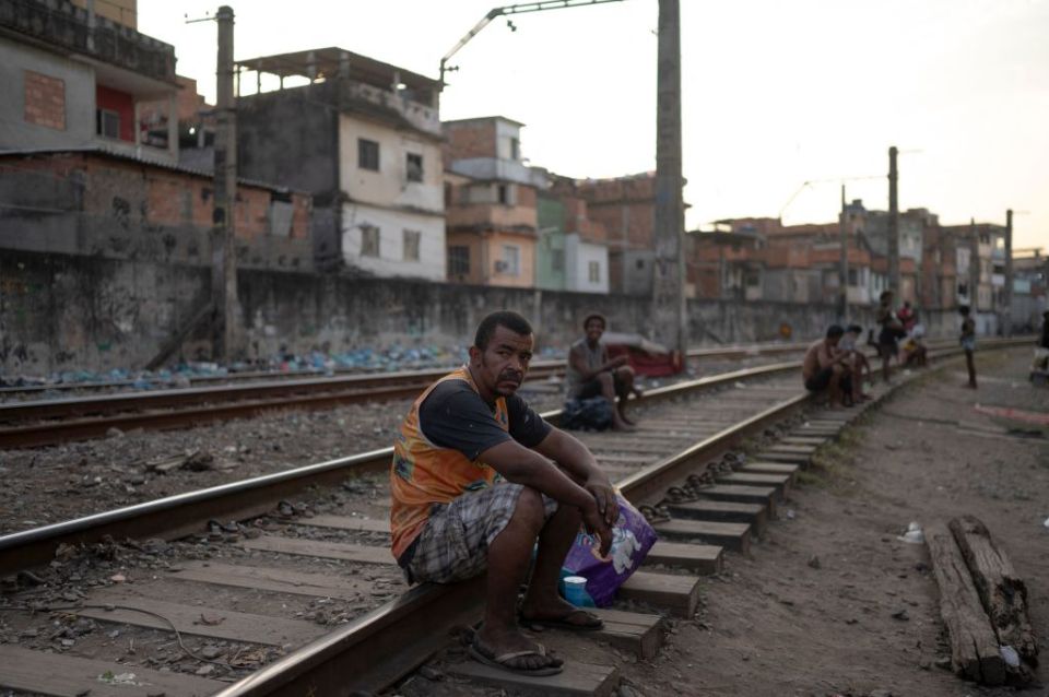 A homeless man sits on a train track in Cracolandia, Rio de Janeiro, Brazil.