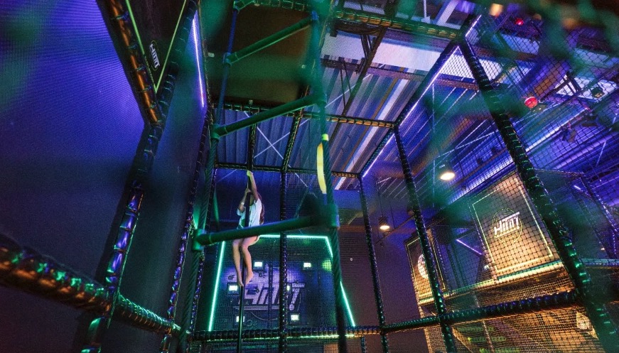 Girl climbing a structure in a brightly lit indoor playground.