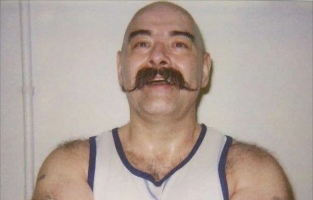 a bald man with a mustache wearing round sunglasses