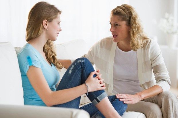 An upset adult daughter ignores her mother who is talking to her.