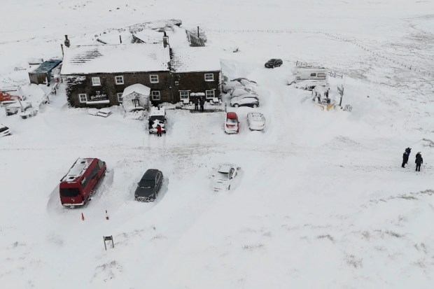 Snow-covered pub and cars in a remote location.