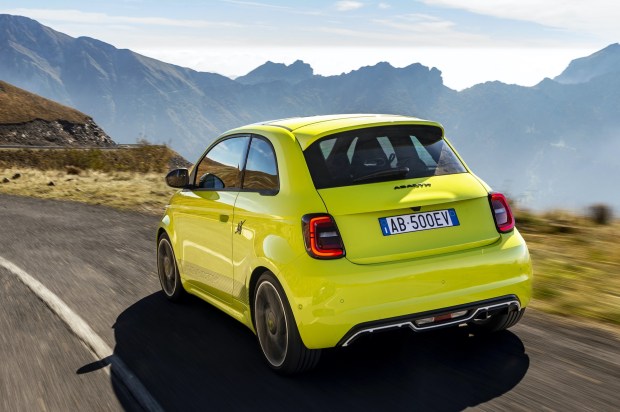 Yellow Abarth 500e electric car driving on a mountain road.