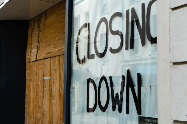 Boarded-up shop window with &quot;Closing Down&quot; painted on it.