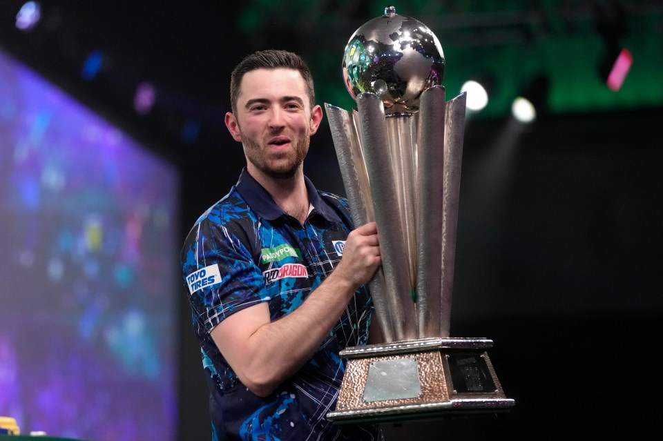 FILE – Luke Humphries of England poses with the trophy after winning the final match against Luke Littler of England at the World Darts Championship, in London, Wednesday, Jan. 3, 2024. (AP Photo/Kin Cheung, File)