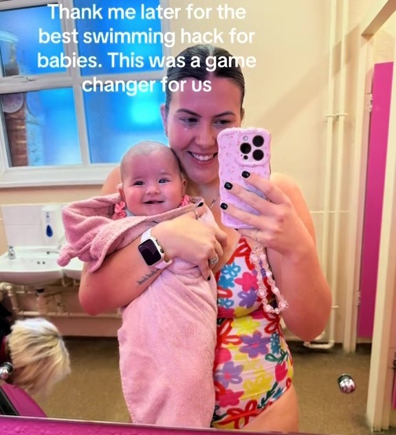 A mother holding a baby wrapped in a towel after swimming.