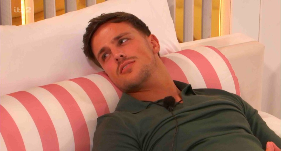 Luca Bish from Love Island lying on a bed.