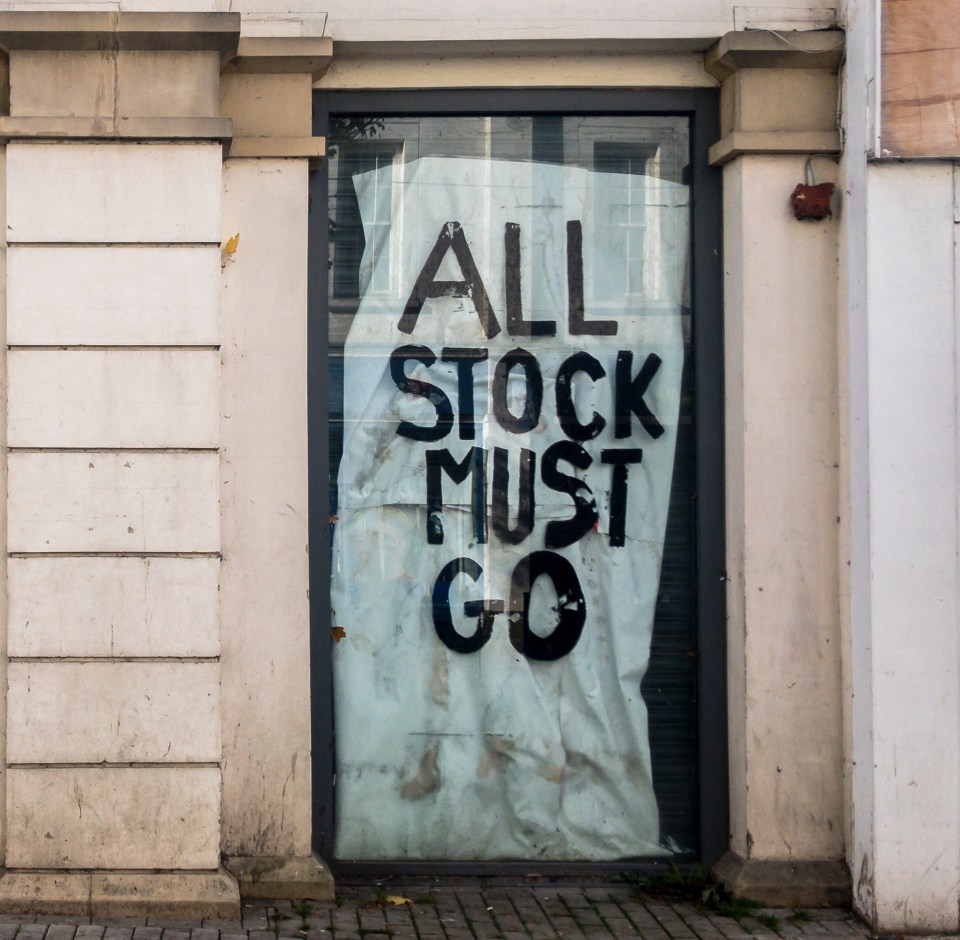 Closed shop windows with signs reading "Closing Down" and "All Stock Must Go".