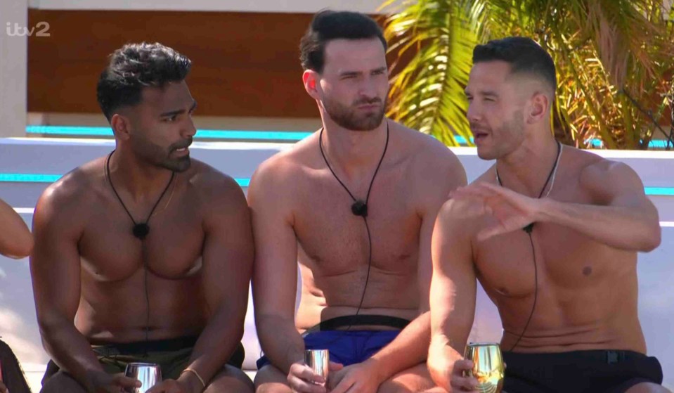 Three shirtless men on Love Island talking and drinking.