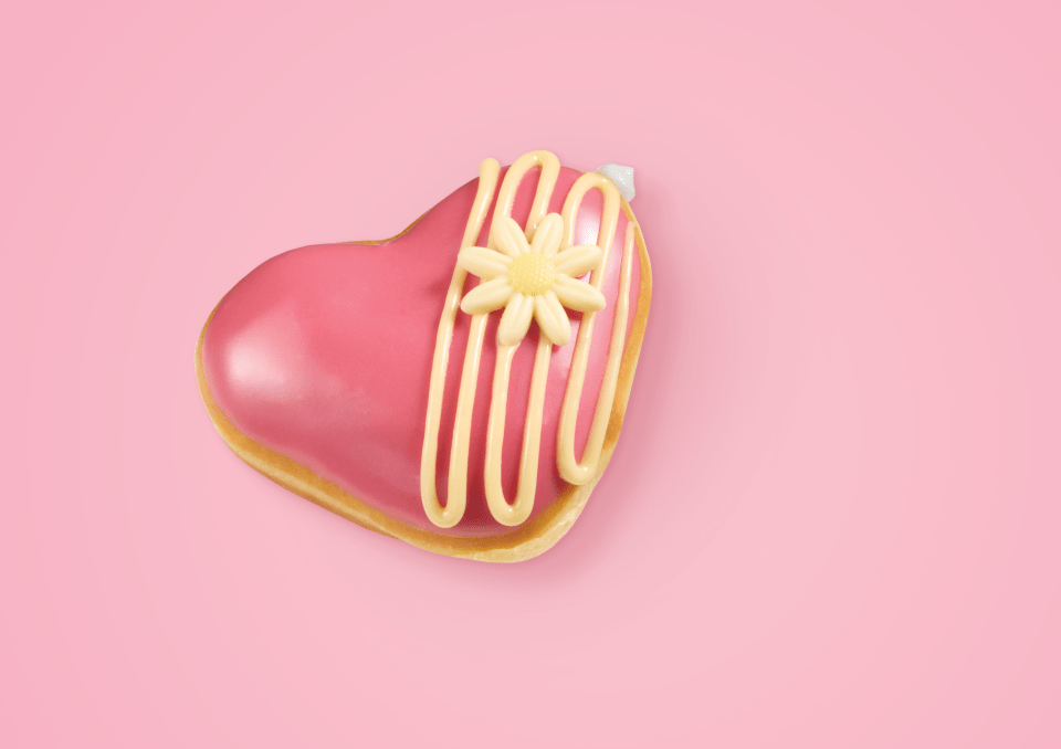 Pink heart-shaped donut with yellow icing and a white daisy.