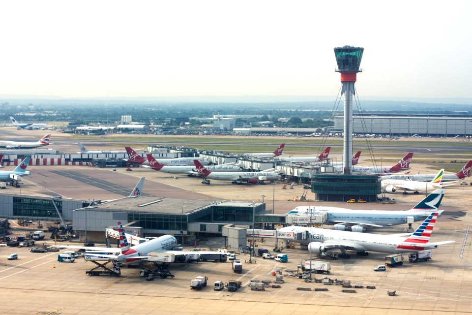 London Heathrow Airport with multiple airplanes and the air traffic control tower.