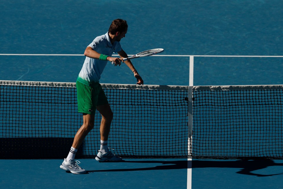 Tennis player Daniil Medvedev hitting a net camera with his racket.