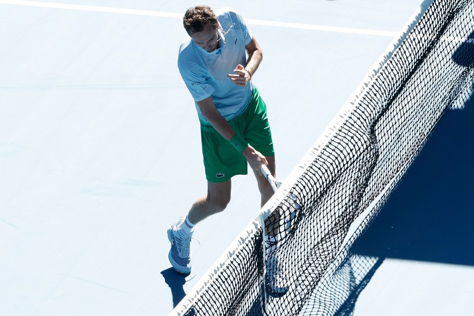 Daniil Medvedev hitting a tennis net with his racket.