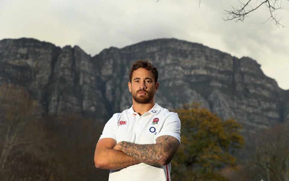 Danny Cipriani in England rugby shirt, arms crossed.