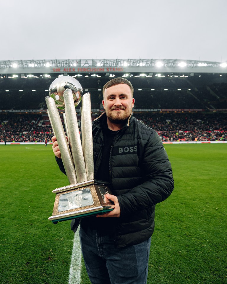 Luke Littler, Darts World Champion, holding his trophy at Old Trafford.