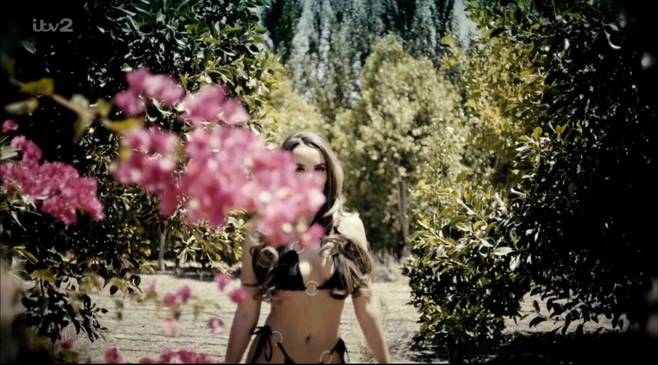 Woman in bikini walking through garden.