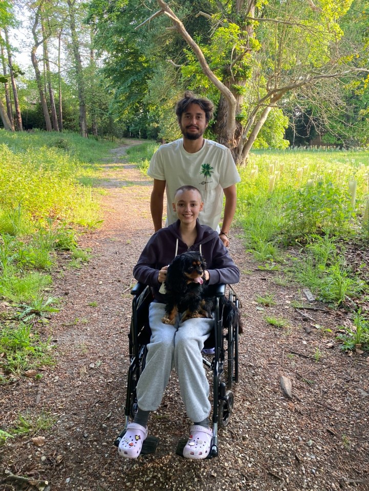 Teenage girl in wheelchair with her brother and dog on a path.