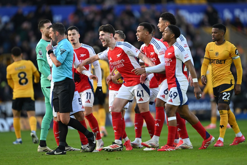 Arsenal player reacts to being sent off by a referee.