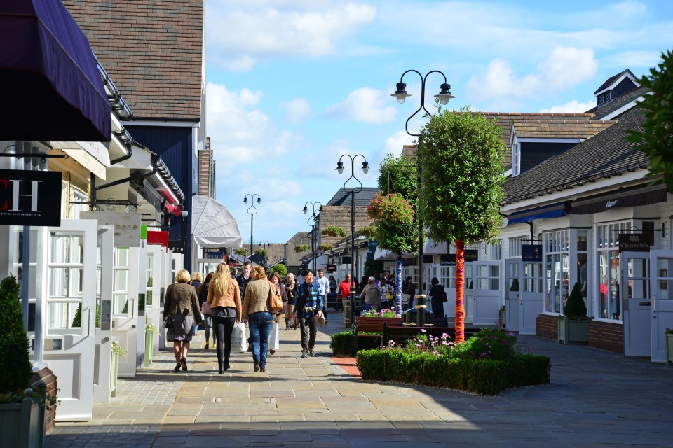 Shoppers walking through Bicester Village outlet shopping center.