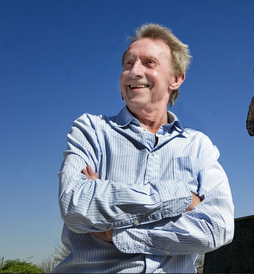 Denis Law standing with arms crossed.