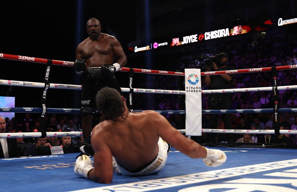 Derek Chisora standing over a fallen Joe Joyce in a boxing match.