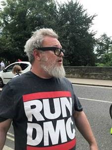 Image of a man wearing a Run DMC t-shirt, sought in connection with a missing boy.