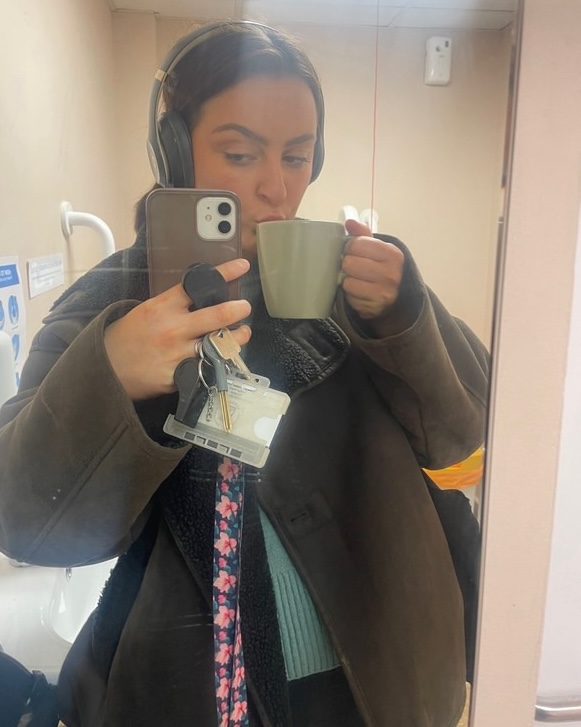 Woman drinking tea while holding her phone and keys.