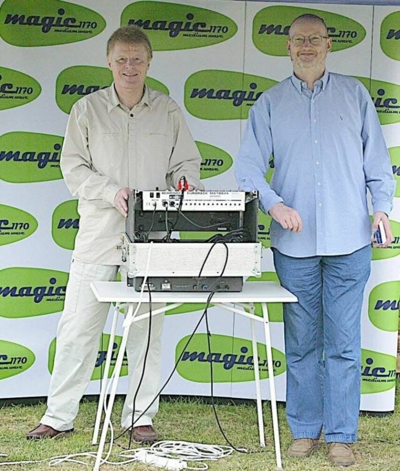 Two men standing behind a soundboard.