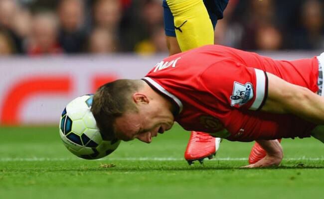 Soccer player on the ground with head near soccer ball.