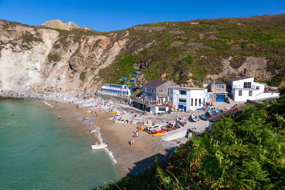 Trevaunance Cove beach in St. Agnes, Cornwall, with people swimming and relaxing.