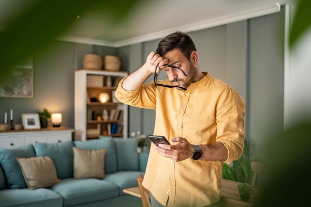 Man looking upset while reading bad news on his phone.