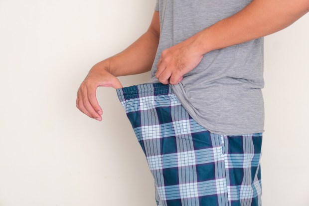 Man adjusting his plaid pajama pants.