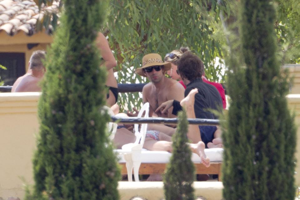 Liam Gallagher and friends sunbathing by a pool.