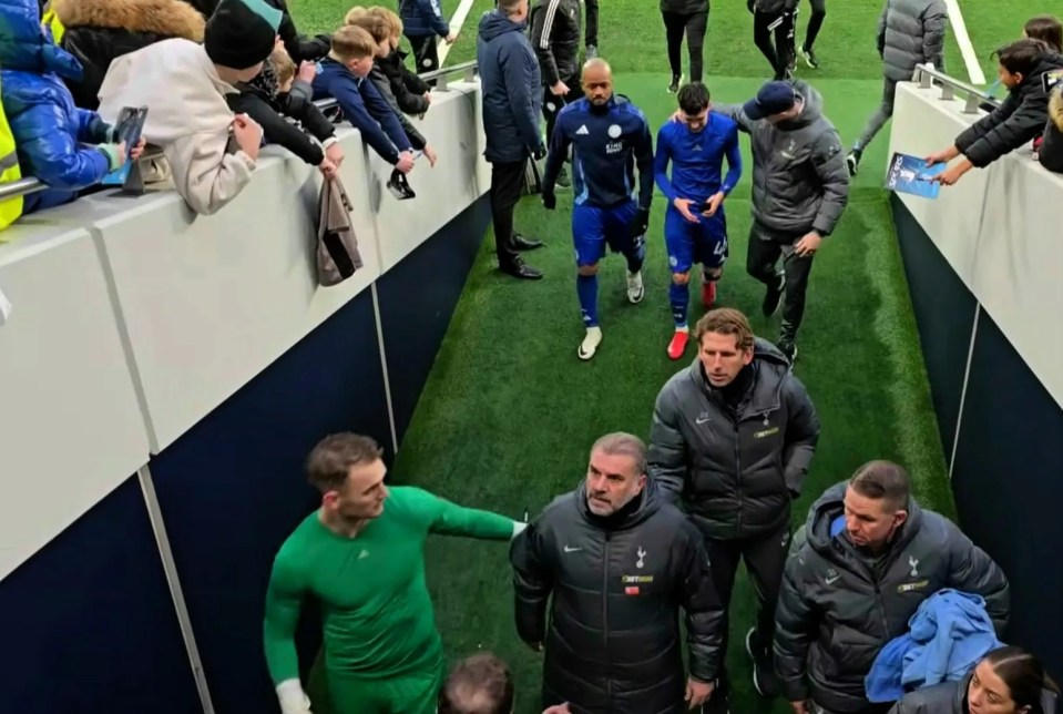 Soccer players and coaches walking down a tunnel.