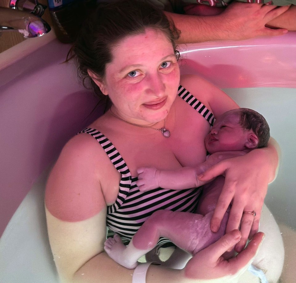 A mother and father holding their newborn baby in a hospital birthing tub.