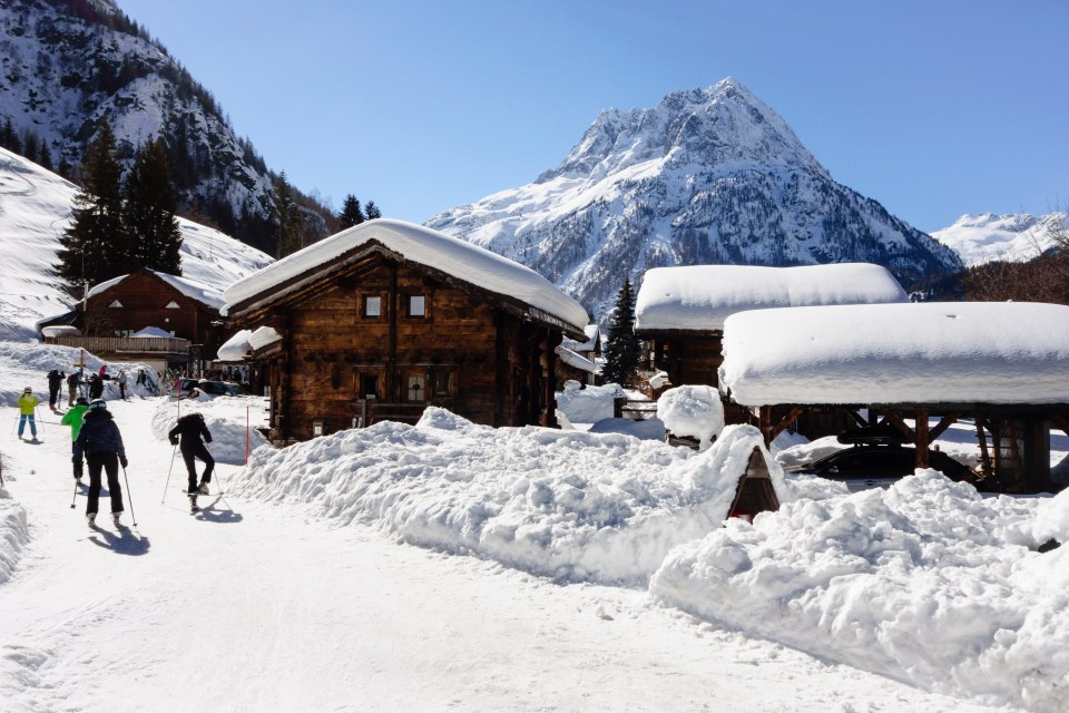 Skiers approaching a snow-covered Alpine village.