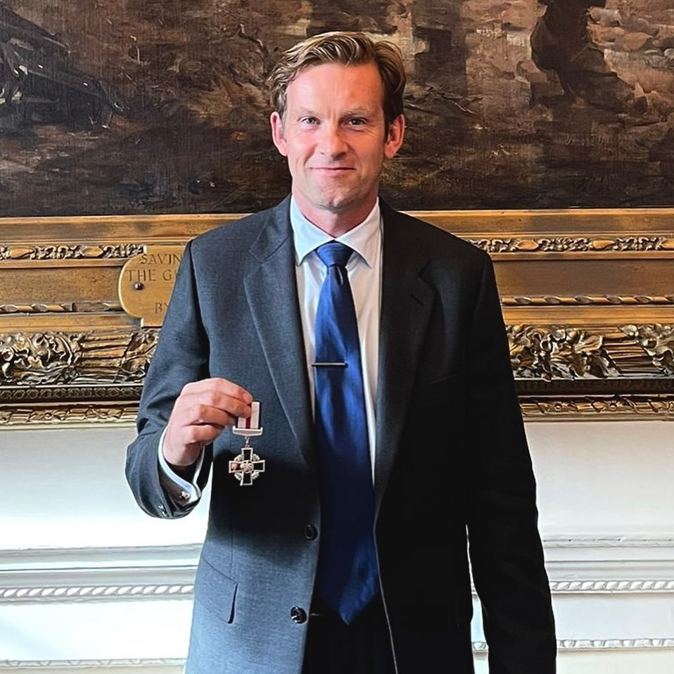 Man in suit holding a medal.