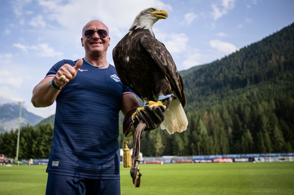 A man in a Lazio jersey holds up a bald eagle, giving a thumbs up.