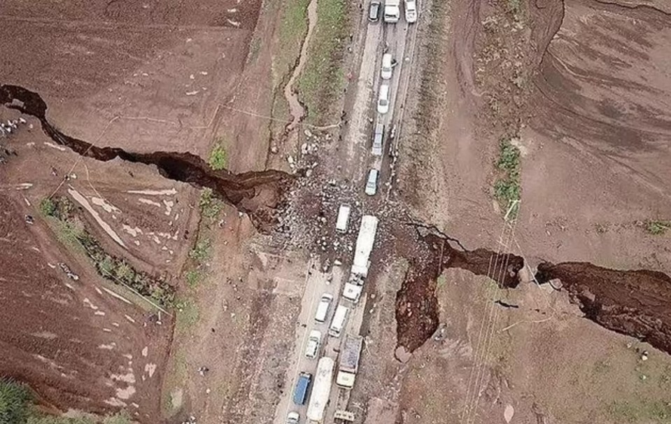 Aerial view of a large crack in the earth splitting a road.