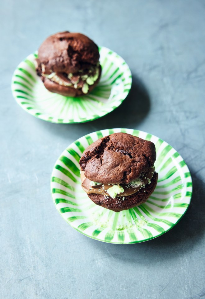 Two chocolate sandwich cookies on green and white striped plates.