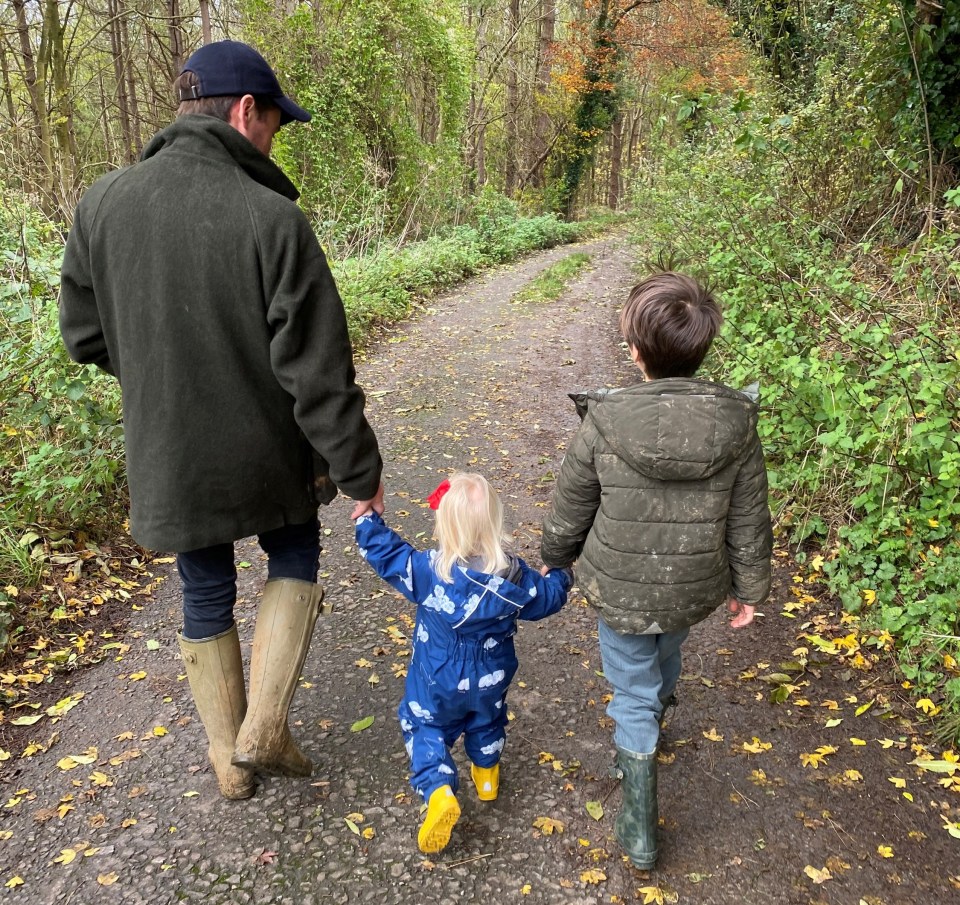 A man and two children walking down a path in a wooded area.