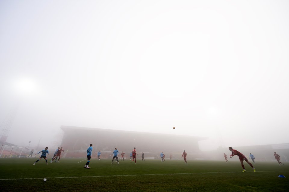 Soccer players on a foggy field.