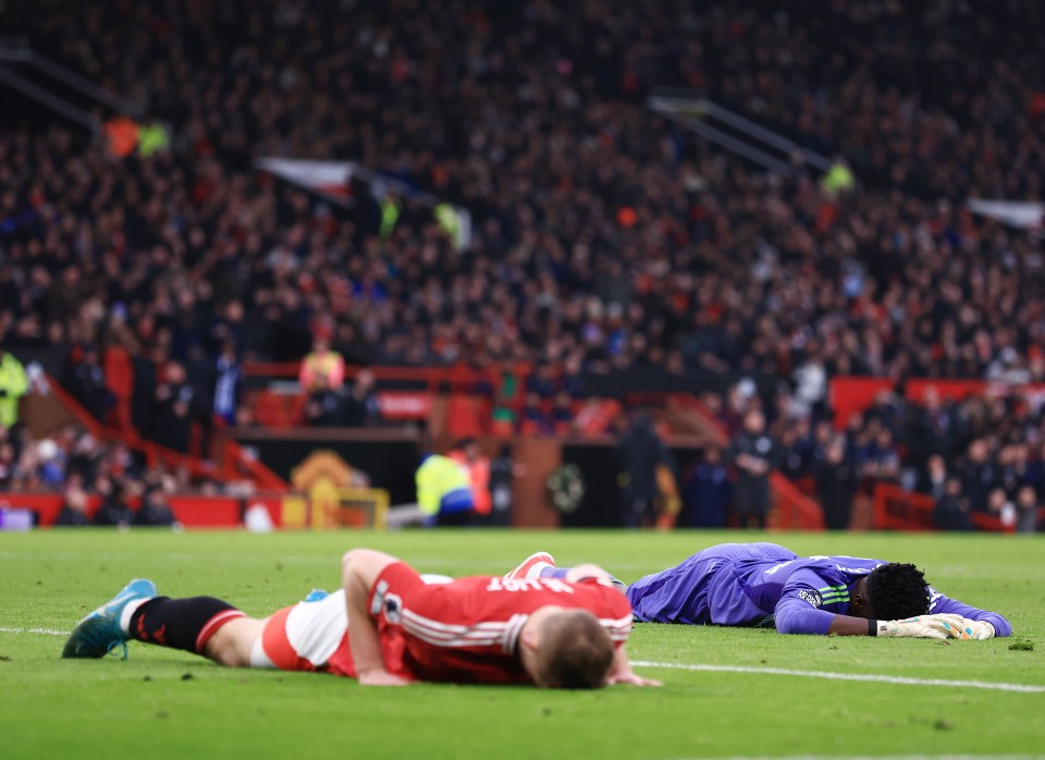 Two dejected soccer players lying on the field.