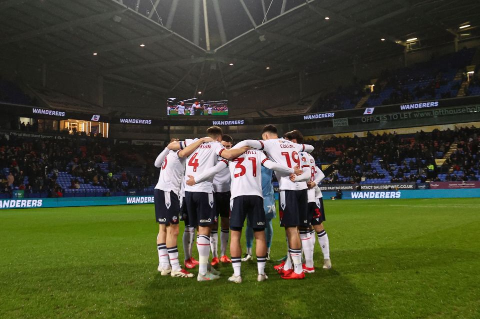 Bolton Wanderers players huddled together on the field.