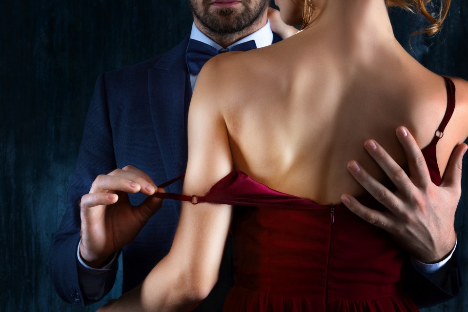 A man adjusting the strap of a woman's dress.