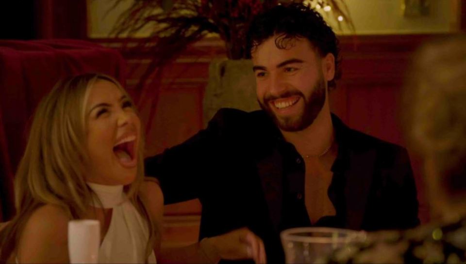 A man and woman laughing together at a table.