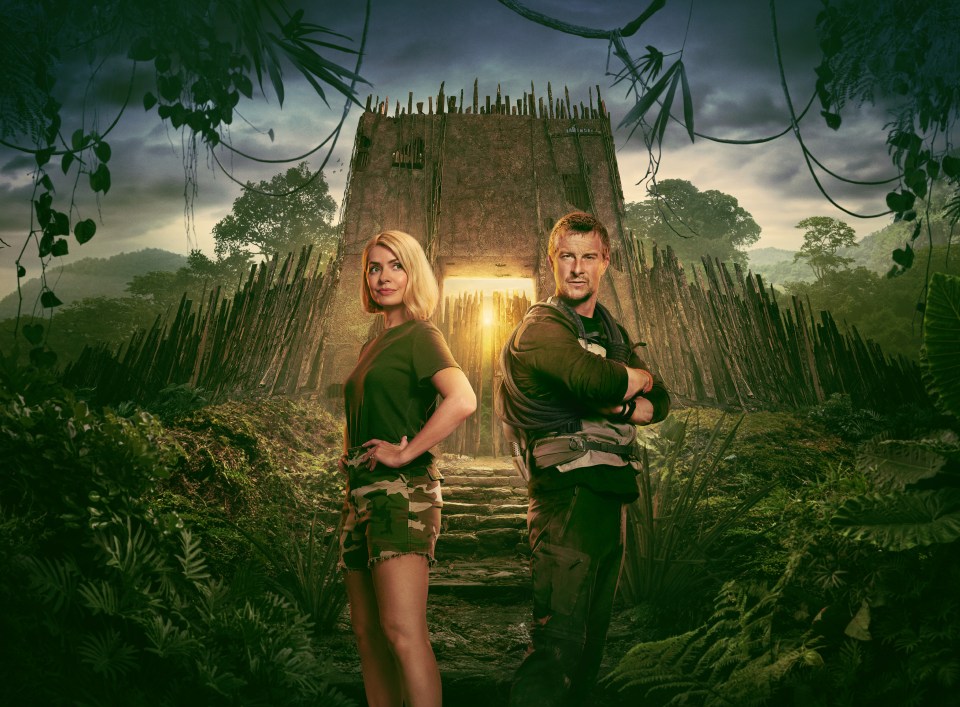 Holly Willoughby and Bear Grylls standing before a jungle structure.