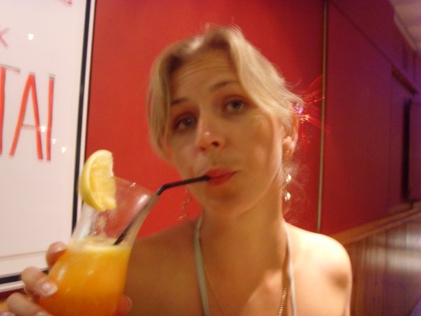 Woman with blonde hair enjoying a cocktail.