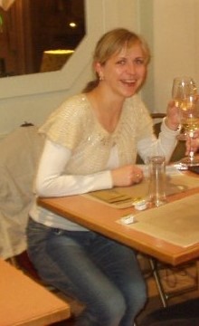 Woman sitting at a table, holding a glass of wine.