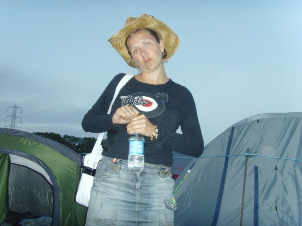 Woman in a straw hat holding a water bottle at a campsite.